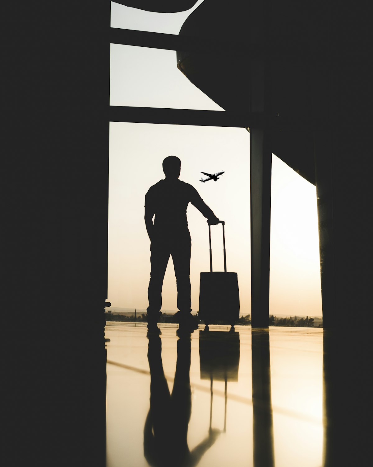 Silhouette of a traveler with luggage inside an airport terminal